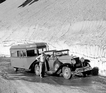 Featured is a vintage photo depicting a 1933 auto with attached trailer at Glacier National Park, specifically on the Logan Pass Hwy.  In July!  The owners of the rig were visitors to the Park from California.  Photo by Nat'l Park photographer George Grant.
